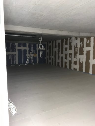 Leerer Raum mit weißer Wandverkleidung und sichtbar bearbeiteten Wänden.